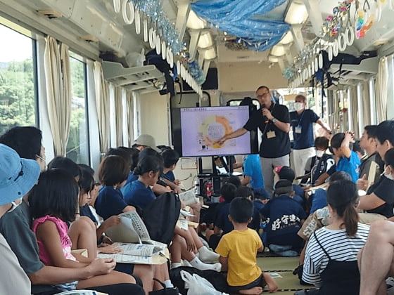 高知県・森田さんの講義を貸切列車内で真剣に聞いている子ども達の様子